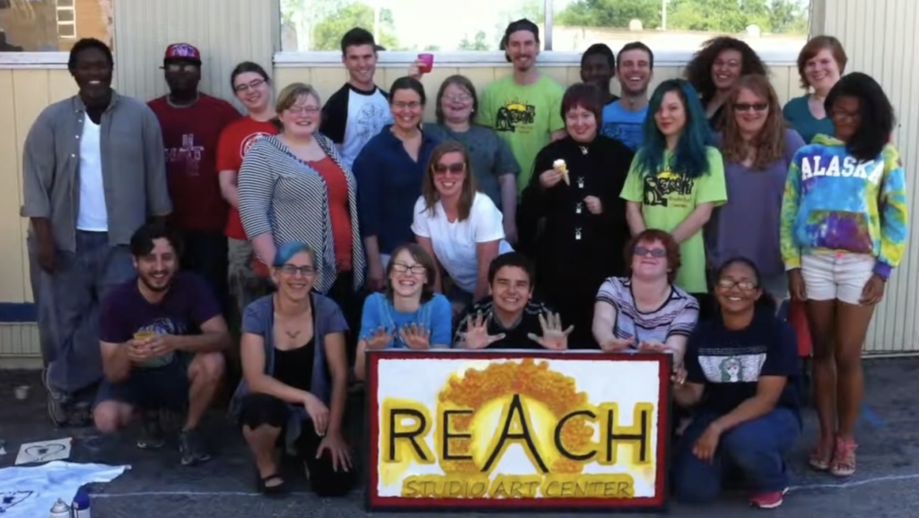 Still from REACH art studio Smiling group of teachers and students outside REACH studio